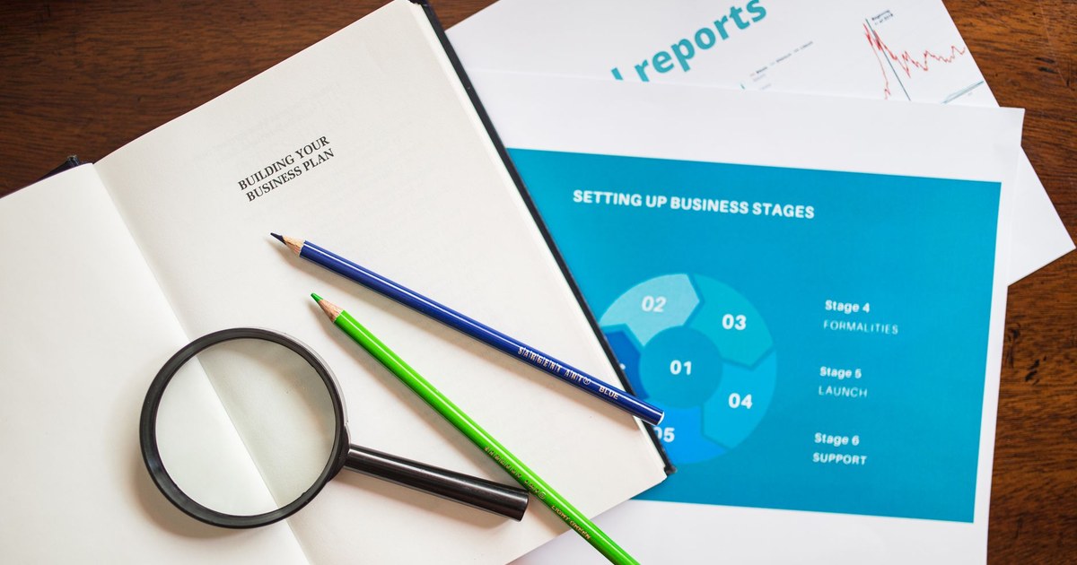 A clipboard checklist beside a magnifying glass on a desk, representing a pre-audit gap review