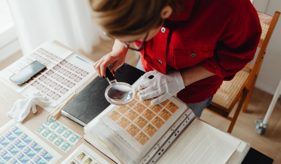 A magnifying glass resting on a stack of printed documents with one page marked by a ribbon