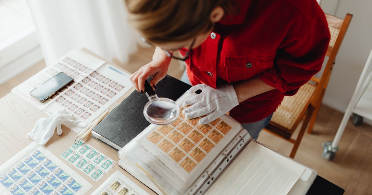 A magnifying glass resting on a stack of printed documents with one page marked by a ribbon